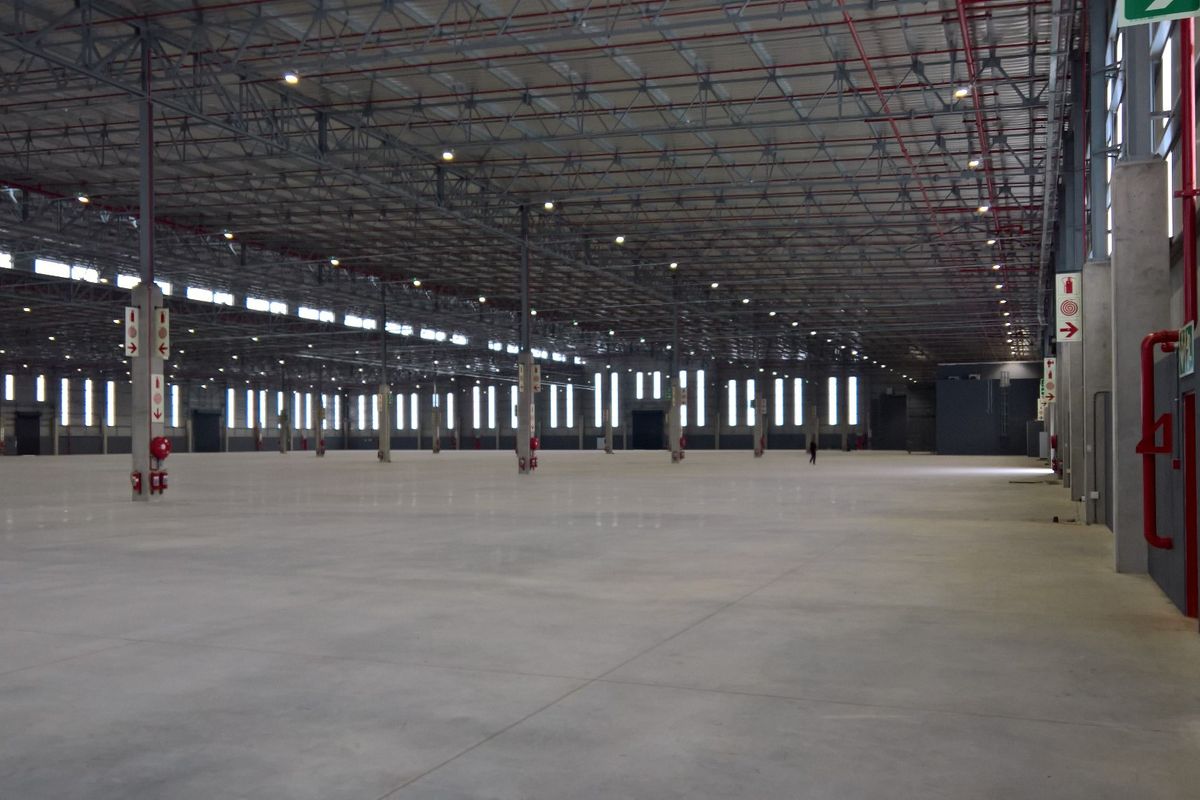 Expansive industrial warehouse space featuring high ceilings, polished concrete flooring, integrated fire safety systems, and ample natural light through perimeter windows.