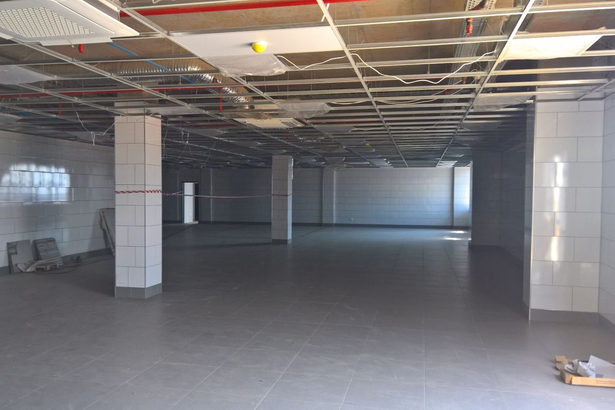 Large open-plan industrial space featuring tiled walls, tiled flooring, and an unfinished ceiling grid with exposed infrastructure, suitable for various commercial or industrial fit-outs.