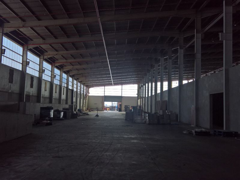 Spacious industrial warehouse featuring a steel portal frame, concrete flooring, and natural light through translucent roof panels, suitable for storage or manufacturing operations.
