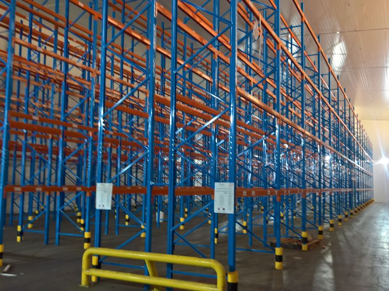 Spacious industrial warehouse interior featuring extensive high-density pallet racking systems, durable concrete flooring, and protective steel safety bollards.