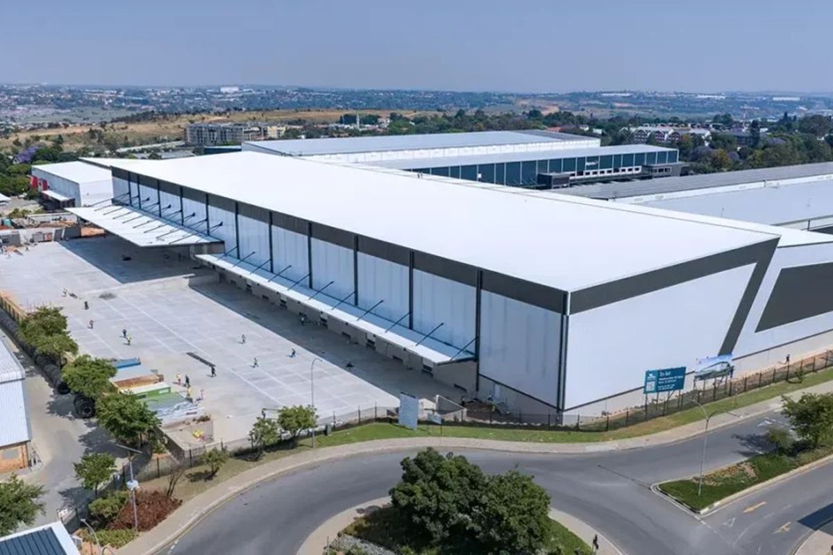 Aerial view of a large industrial warehouse facility featuring extensive loading docks, a paved concrete yard, and modern metal roofing.