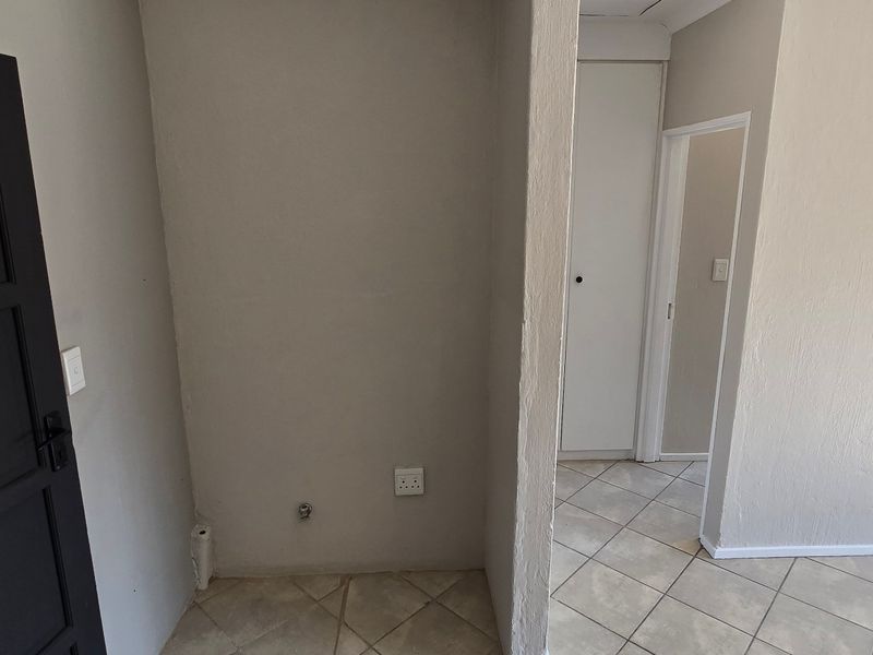 A functional laundry area featuring tiled flooring, dedicated plumbing connections, and an electrical outlet, providing a practical space for laundry appliances.