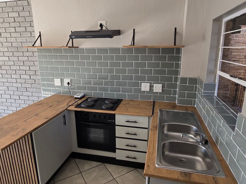 Modern kitchen featuring subway tile backsplash, wooden countertops, built-in oven with hob, extractor fan, and a double bowl stainless steel sink.