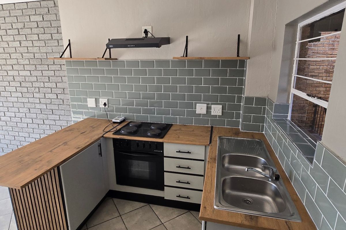 Modern kitchen featuring subway tile backsplash, wooden countertops, built-in oven with hob, extractor fan, and a double bowl stainless steel sink.