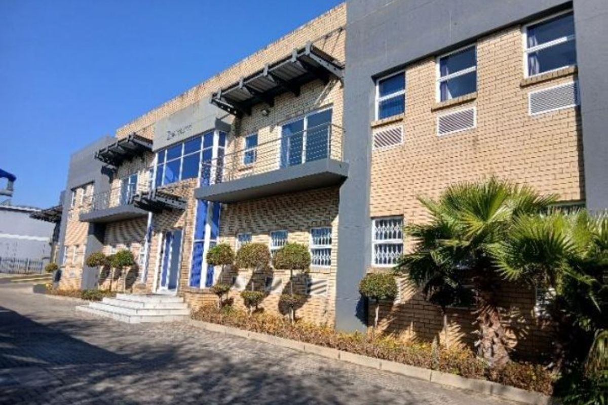 Modern industrial office building featuring a face brick facade, glass curtain walling, and integrated balconies with metal awnings.