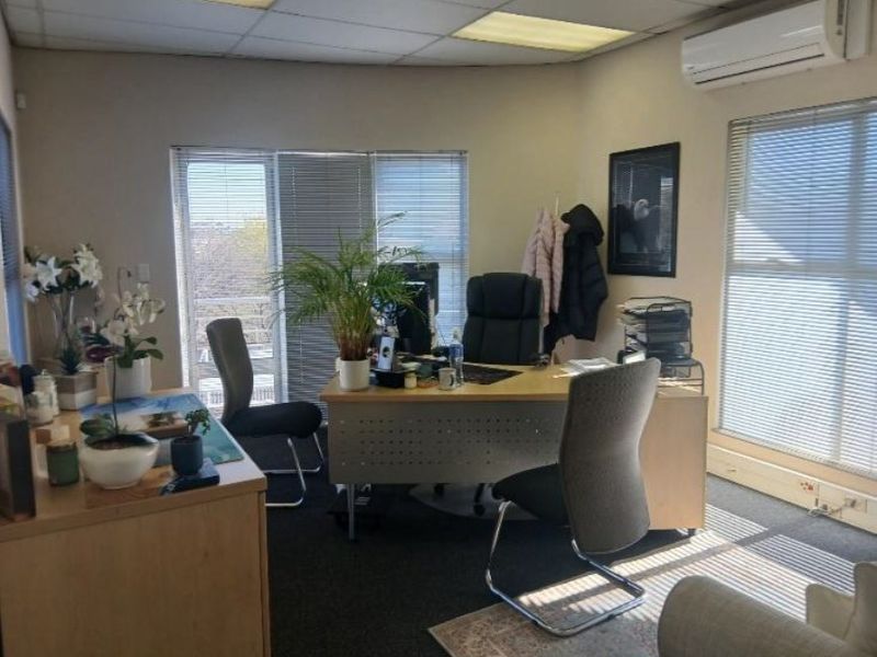 A functional office space featuring a suspended ceiling, split-system air conditioning, and large windows with venetian blinds, providing ample natural light.