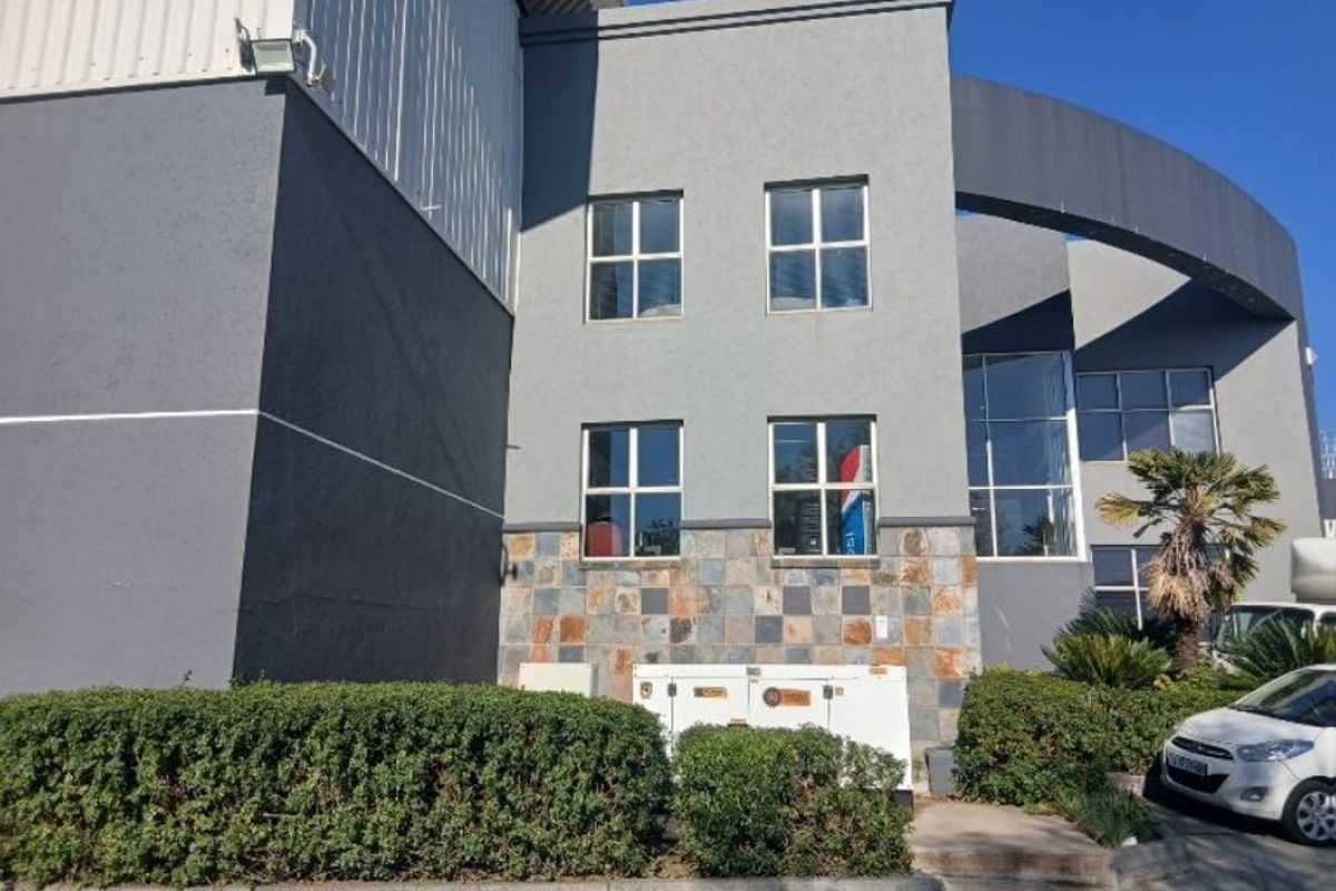 Front elevation of an industrial building featuring grey rendered walls, stone cladding accents, and large fixed windows.