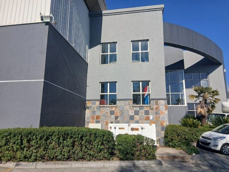 Front elevation of an industrial building featuring grey rendered walls, stone cladding accents, and large fixed windows.