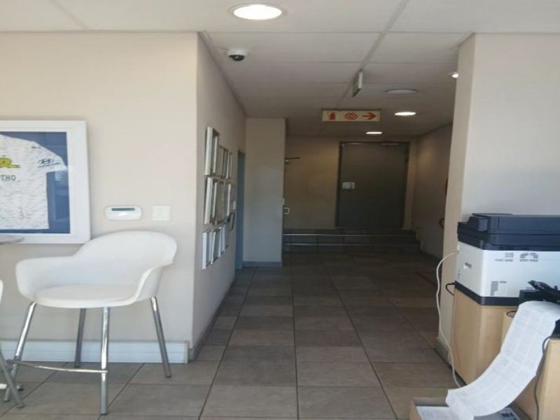 A functional industrial hallway featuring tiled flooring, recessed lighting, and a secure metal door leading to the rear exit.