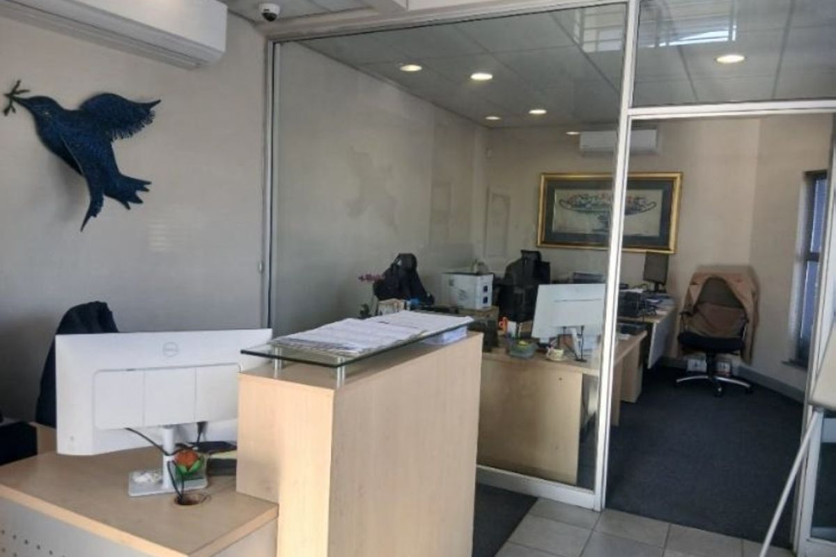 A professional office space featuring a reception area, glass-partitioned private office, recessed lighting, and a combination of carpet and tiled flooring.