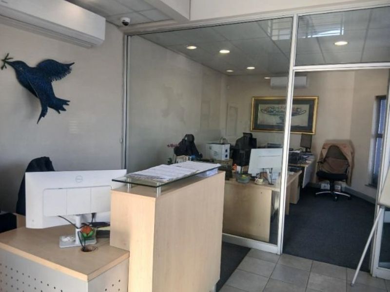 A professional office space featuring a reception area, glass-partitioned private office, recessed lighting, and a combination of carpet and tiled flooring.