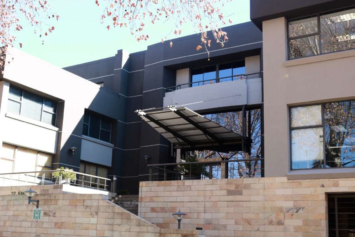 Modern commercial building facade featuring stone cladding, large glass windows, and a prominent metal entrance awning.