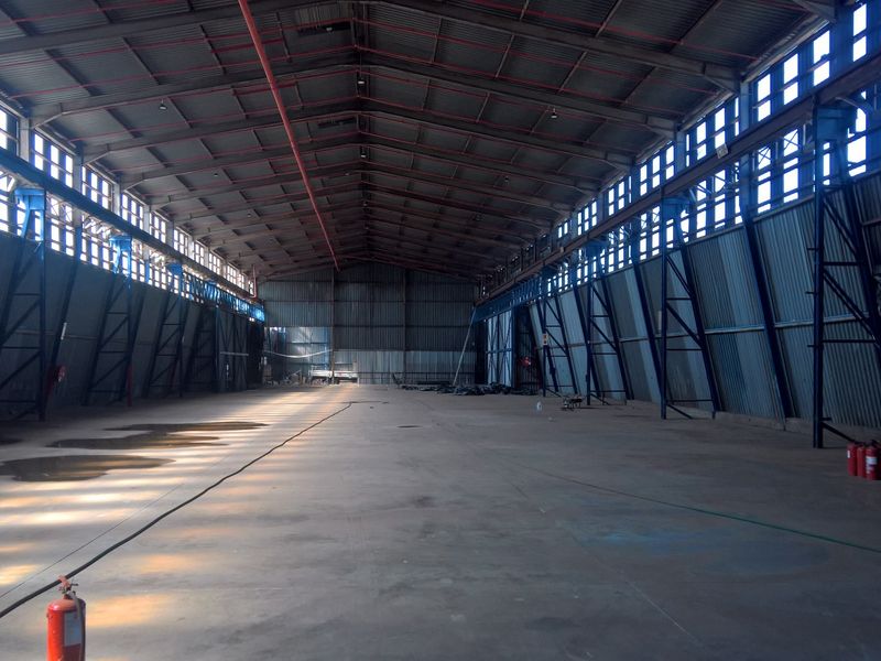 Spacious industrial warehouse featuring a high-clearance steel portal frame, corrugated metal walls, concrete flooring, and integrated fire safety systems.