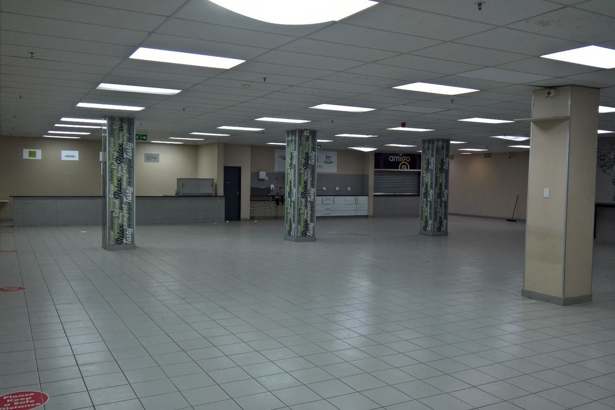 Spacious open-plan industrial or commercial unit featuring tiled flooring, suspended ceilings with recessed lighting, and built-in service counters.