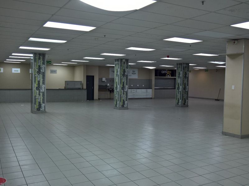 Spacious open-plan industrial or commercial unit featuring tiled flooring, suspended ceilings with recessed lighting, and built-in service counters.