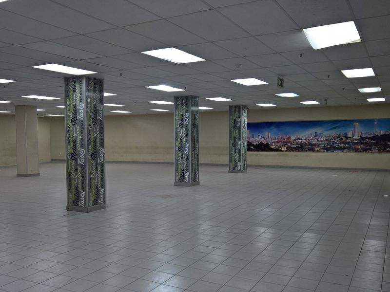 A large, open-plan industrial space featuring a suspended ceiling, recessed lighting, and ceramic tiled flooring, suitable for various commercial or office configurations.