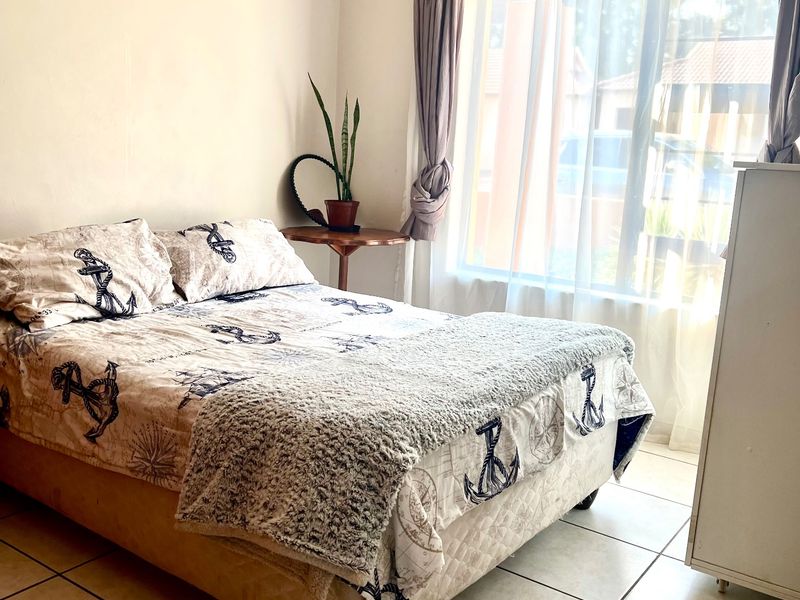 A bright bedroom featuring tiled flooring and a large window that allows for ample natural light.