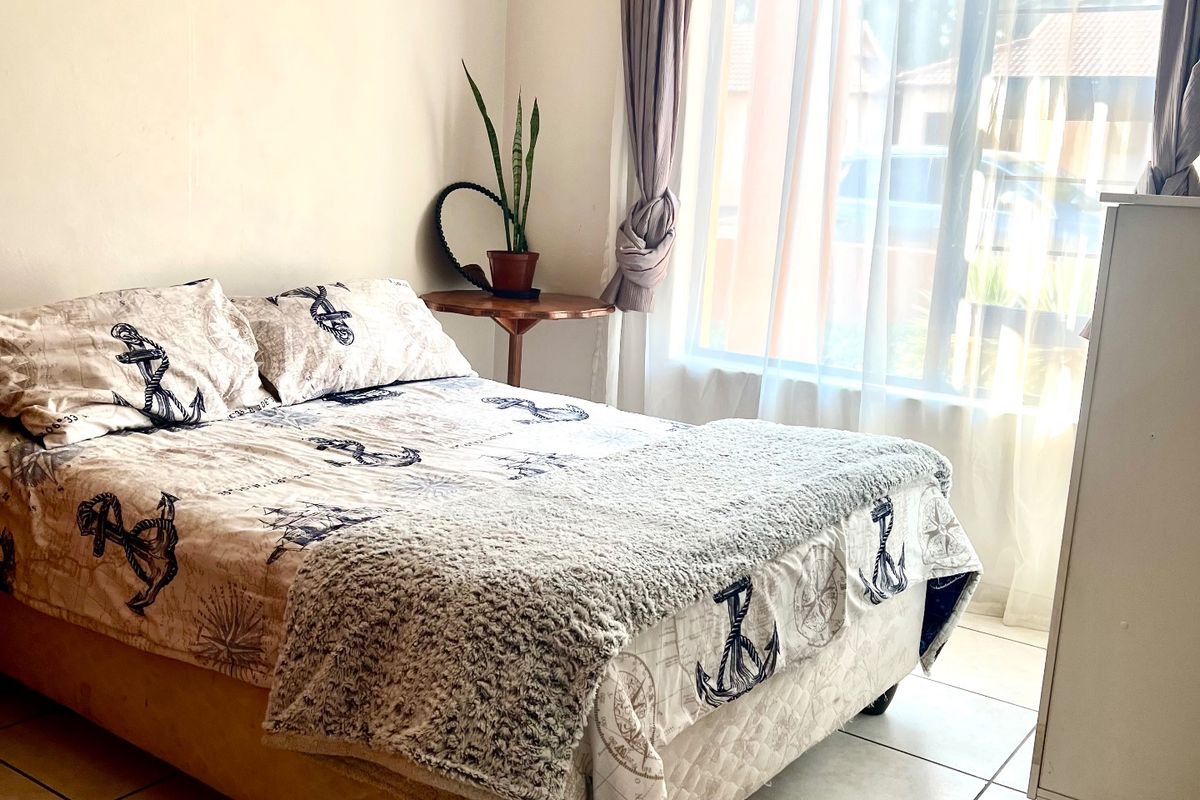 A bright bedroom featuring tiled flooring and a large window that allows for ample natural light.