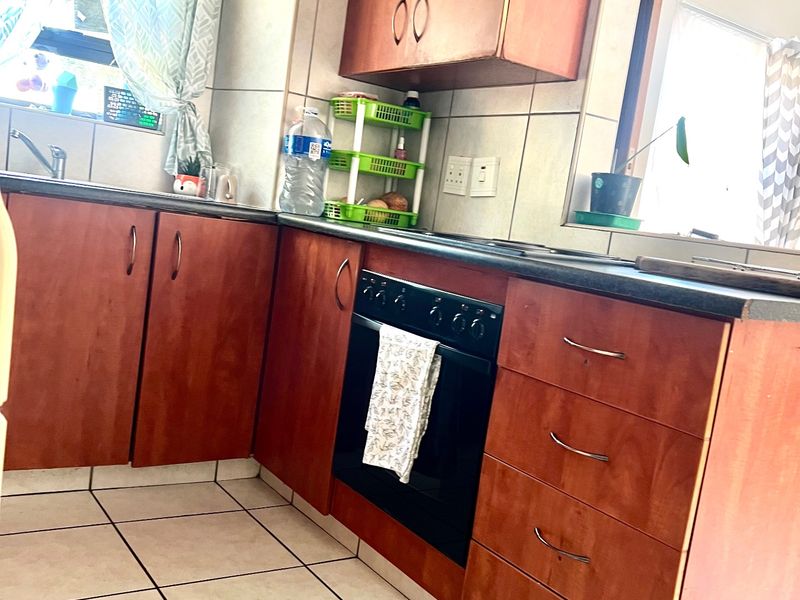 A functional kitchen featuring wood-look laminate cabinetry, a built-in oven, tiled backsplash, and tiled flooring, offering a practical layout for daily use.