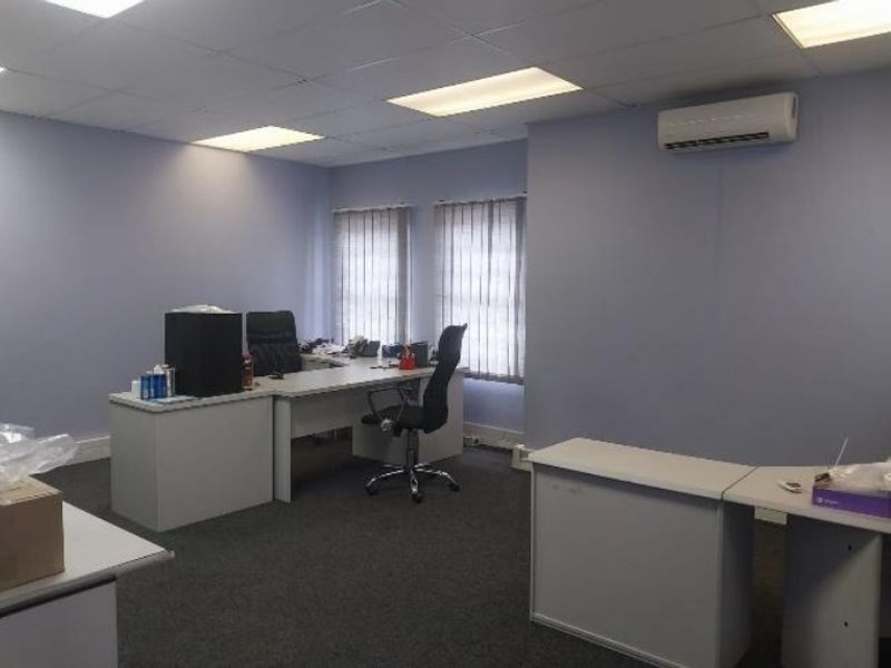 A functional office space featuring a suspended ceiling, recessed lighting, split-system air conditioning, and vertical blinds.