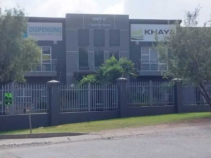 Front elevation of a modern industrial unit featuring steel palisade fencing, electric security, and upper-level balconies with steel railings.
