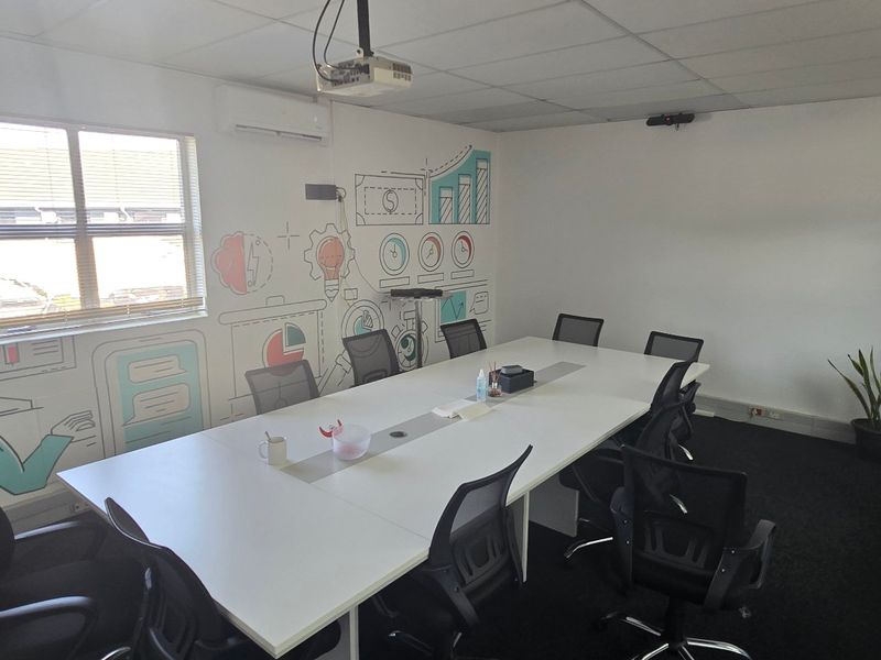 A functional office meeting room featuring a suspended ceiling, integrated air conditioning, a ceiling-mounted projector, and a glass partition wall.