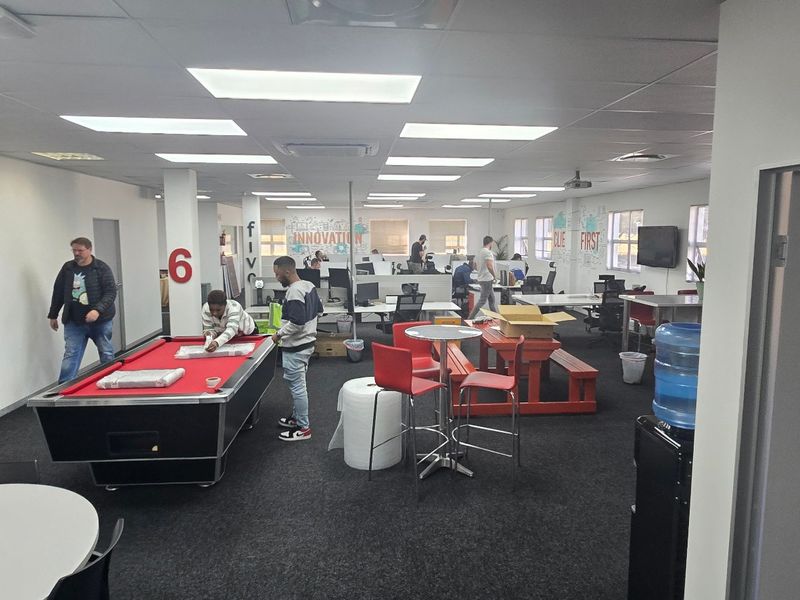 Spacious open-plan commercial office area featuring suspended ceilings, recessed lighting, and carpeted flooring, suitable for a collaborative workspace environment.
