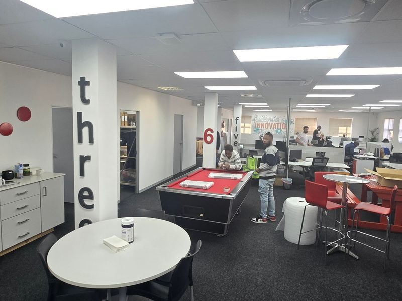 Open-plan commercial office space featuring recessed ceiling lighting, structural columns, and built-in storage cabinetry.