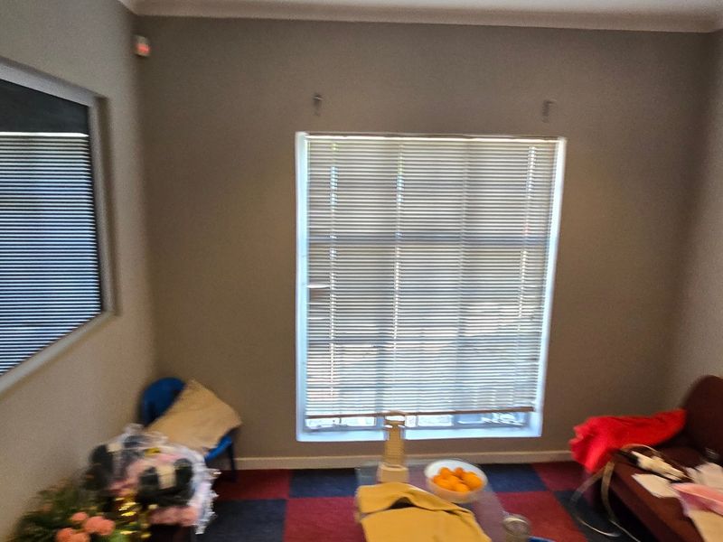 A functional office space featuring neutral walls, coving, and fitted venetian blinds, providing a practical environment for commercial use.