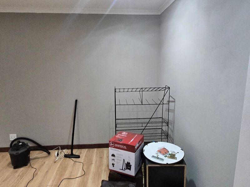 A clean, empty office space featuring neutral grey walls, laminate flooring, and cove cornicing, suitable for a professional workspace.