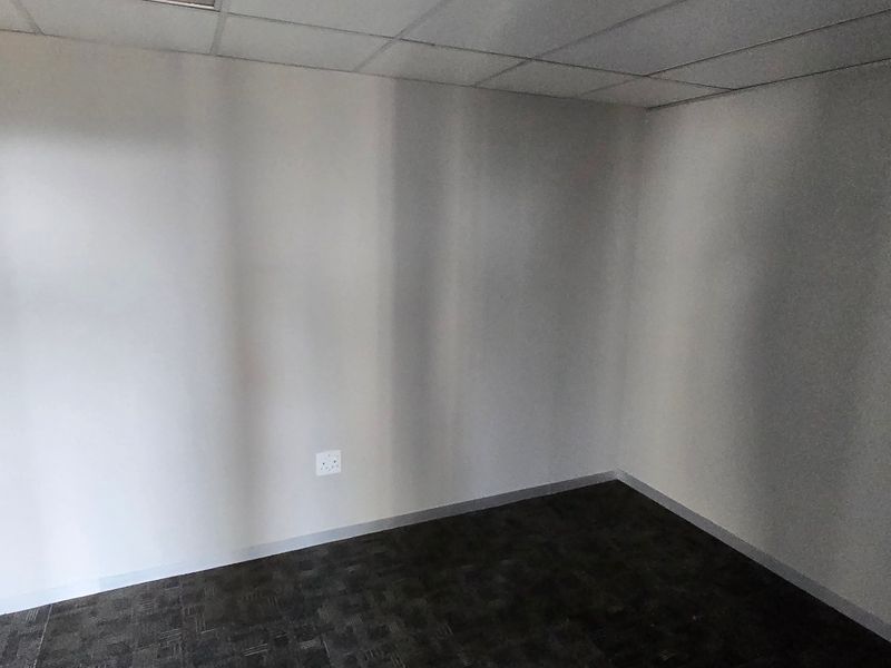 A vacant, neutral office space featuring carpeted flooring and a suspended ceiling, suitable for a professional workspace or private meeting room.