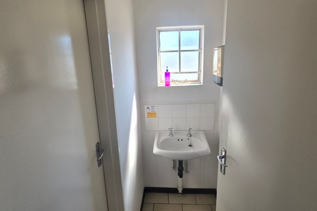 A compact, functional washroom featuring a wall-mounted basin with tiled splashback and tiled flooring.