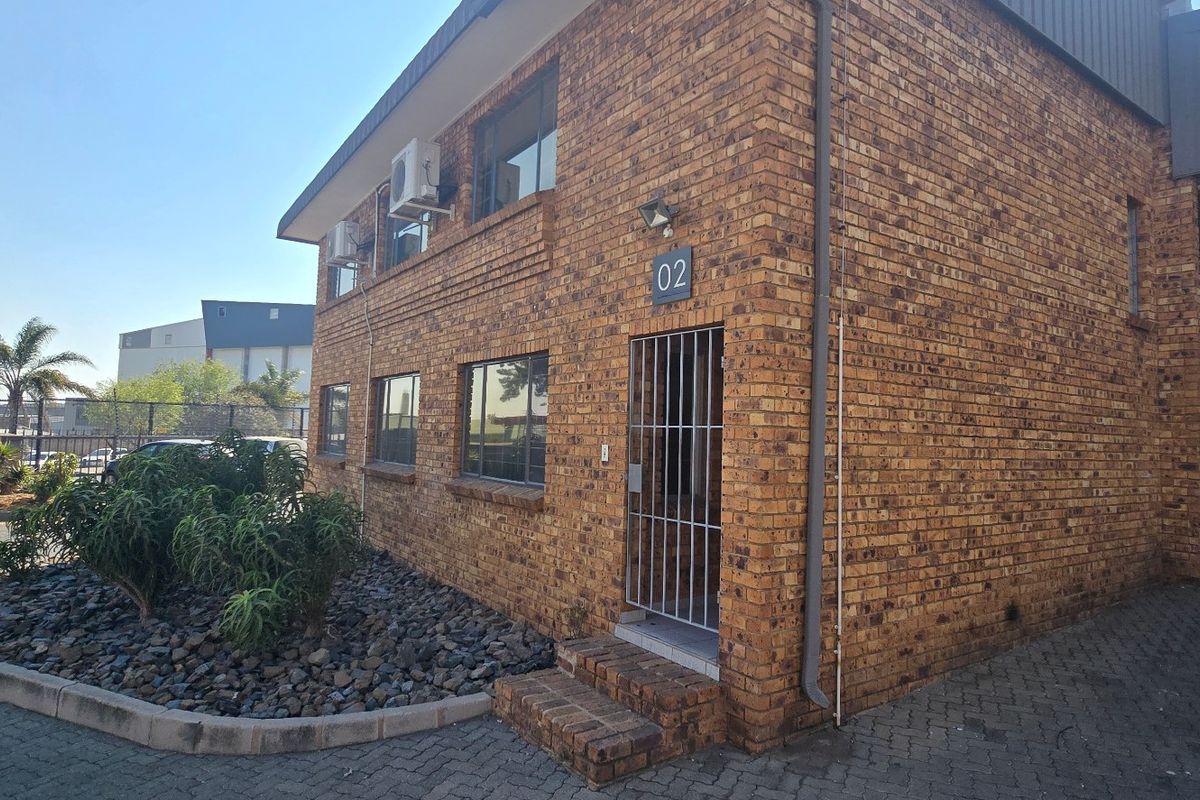 Front elevation of an industrial unit featuring face brick construction, security gate entrance, and an integrated roller shutter door for warehouse access.