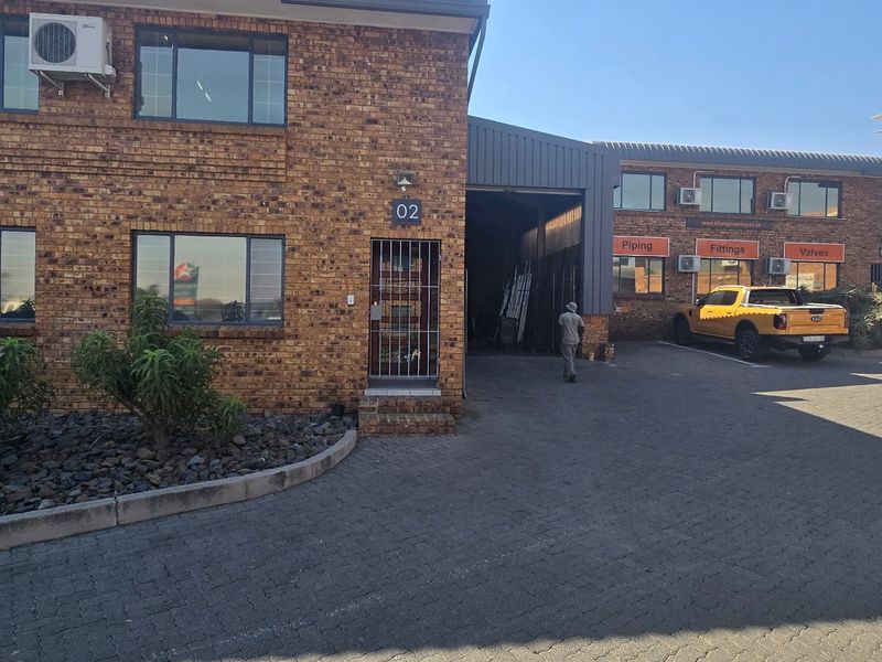 Front elevation of an industrial property featuring face brick construction, paved driveway access, and multiple split-system air conditioning units.