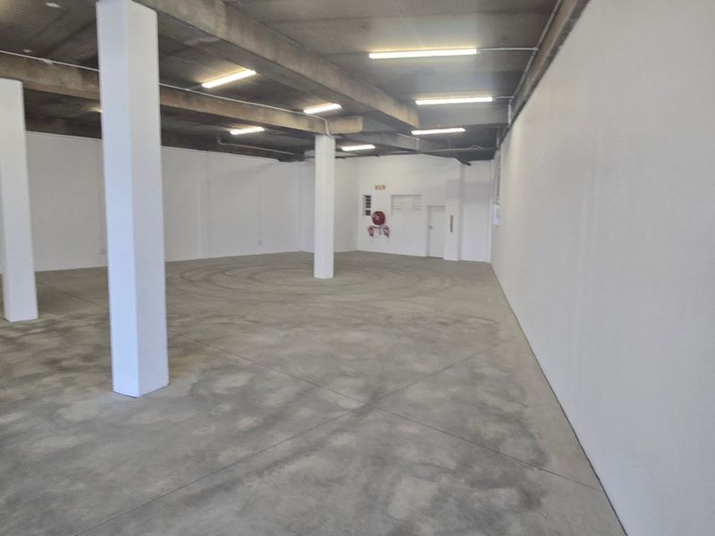 Spacious industrial utility area featuring concrete flooring, exposed ceiling beams, and structural columns, suitable for storage or workshop use.