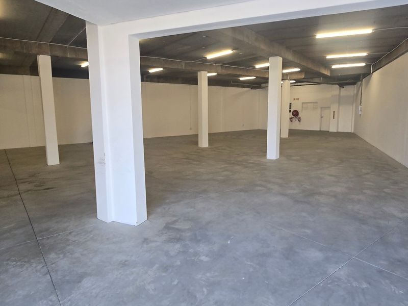Spacious industrial utility area featuring polished concrete flooring, exposed concrete ceilings, and structural support columns, suitable for storage or workshop use.