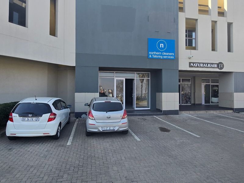 Front exterior view of a commercial industrial unit featuring a paved parking area and glass entrance door with signage.