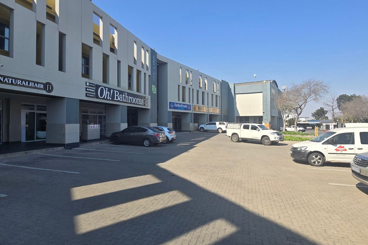 Front exterior view of a multi-tenant industrial or commercial complex featuring paved parking and modern storefront facades.