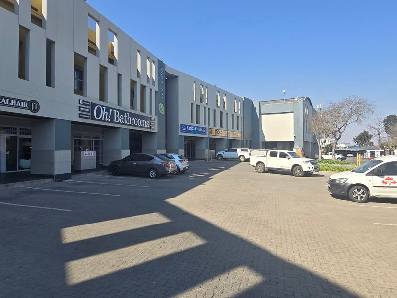 Front exterior view of a multi-tenant industrial or commercial complex featuring paved parking and modern storefront facades.