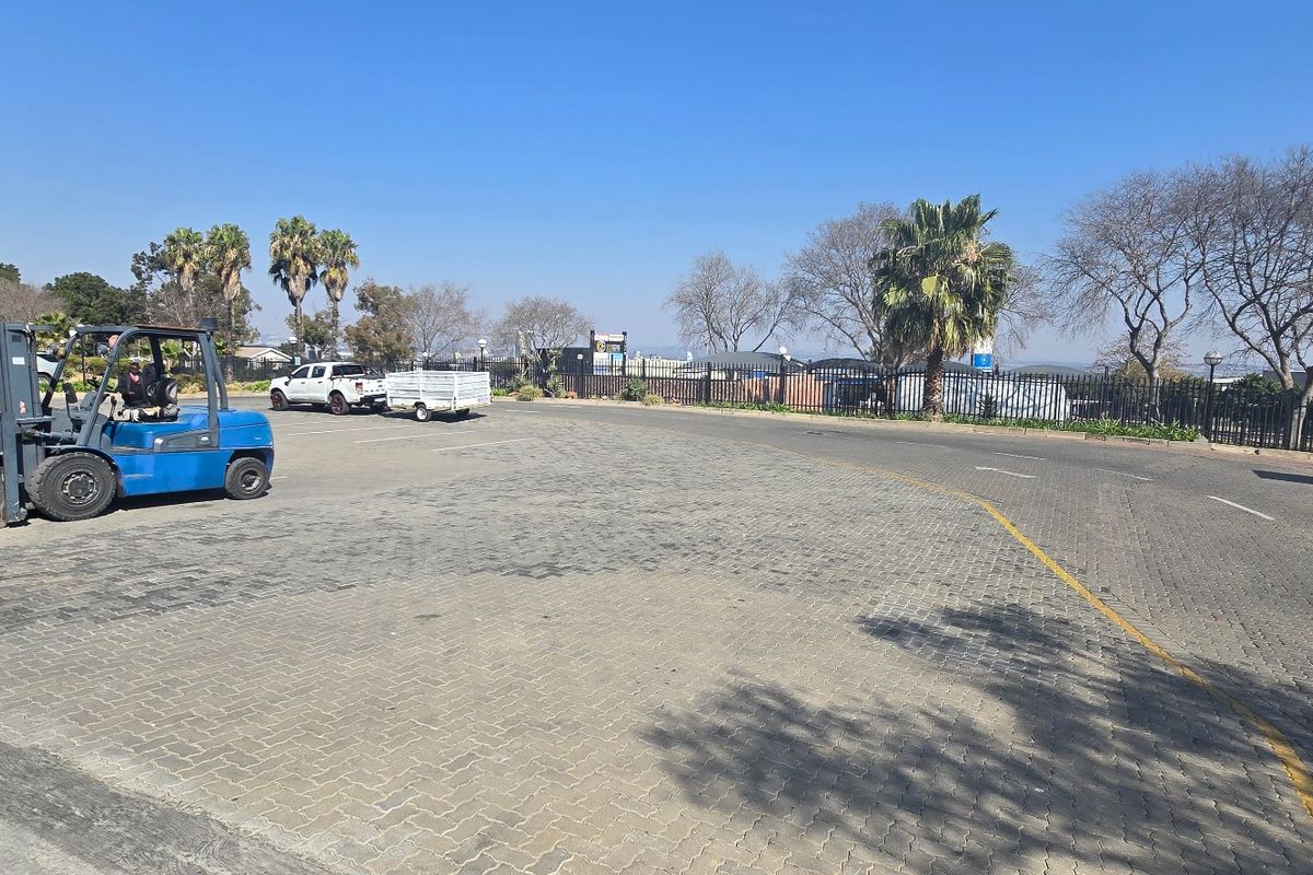 Industrial exterior view featuring a paved yard area, perimeter fencing, and building signage.
