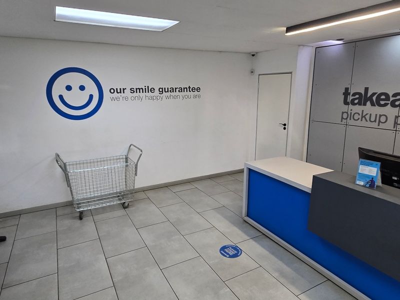 A clean and professional industrial pickup point entrance featuring a modern reception desk, tiled flooring, and branded wall signage.