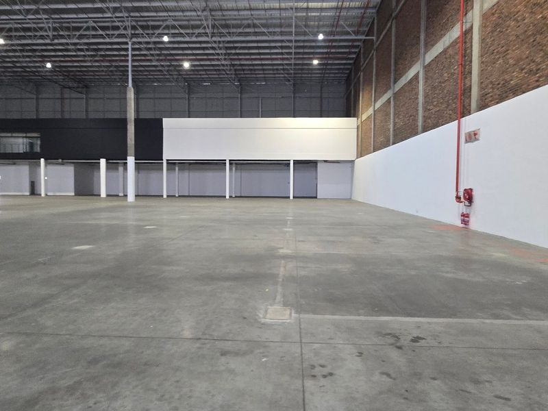 Spacious industrial warehouse unit featuring high ceilings with exposed steel trusses, concrete flooring, and integrated fire safety systems.