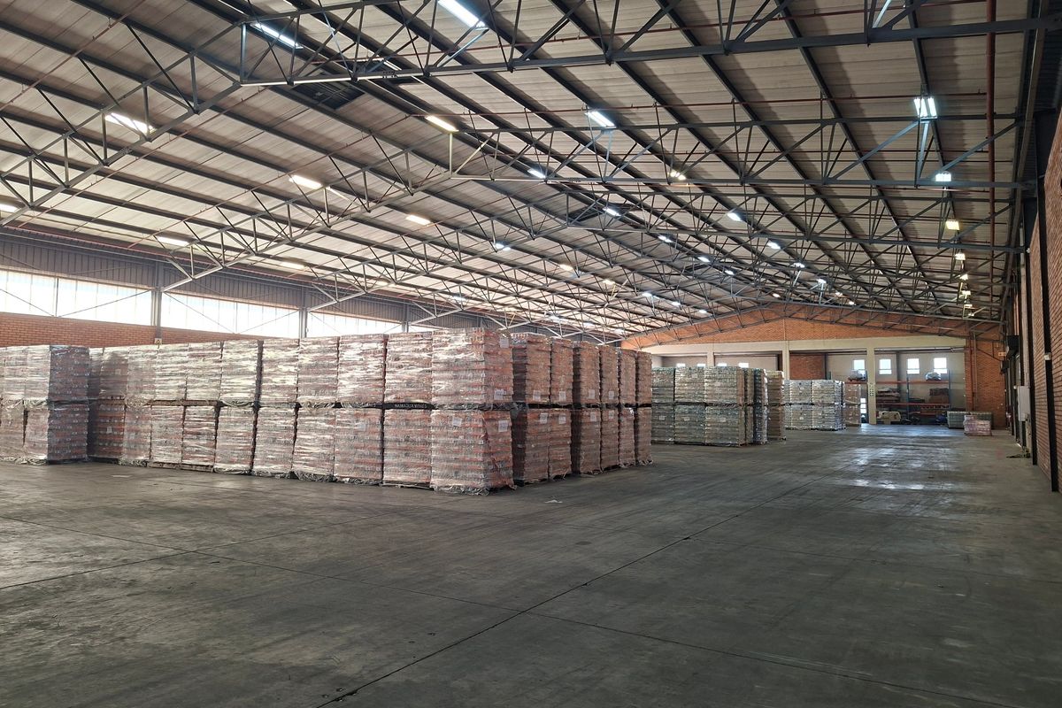 Spacious industrial warehouse featuring high-clearance steel truss roofing, durable concrete flooring, and efficient high-bay lighting, suitable for large-scale storage or manufacturing operations.