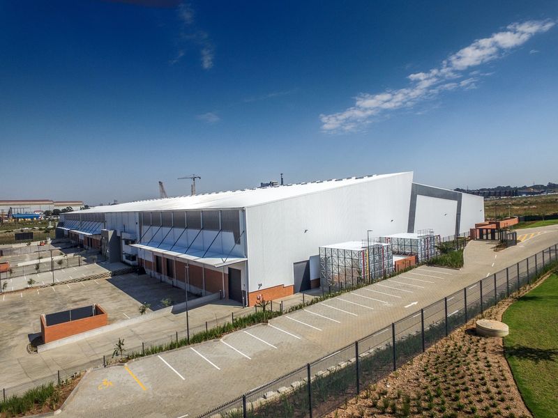 Aerial view of a modern industrial warehouse facility featuring extensive parking, secure perimeter fencing, and dedicated loading bay access.