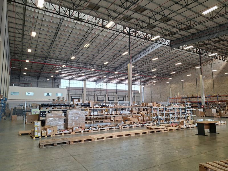 Spacious industrial warehouse featuring high-clearance exposed steel truss roofing, polished concrete floors, and integrated fire sprinkler systems, suitable for logistics or manufacturing operations.