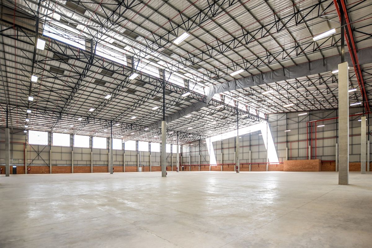 Spacious industrial warehouse featuring high ceilings with exposed steel trusses, polished concrete flooring, and integrated fire sprinkler systems.