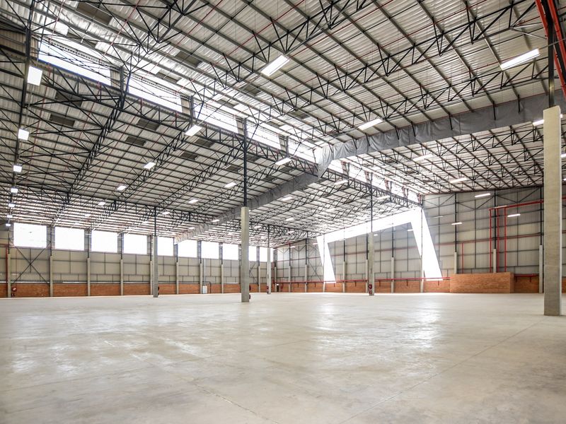 Spacious industrial warehouse featuring high ceilings with exposed steel trusses, polished concrete flooring, and integrated fire sprinkler systems.