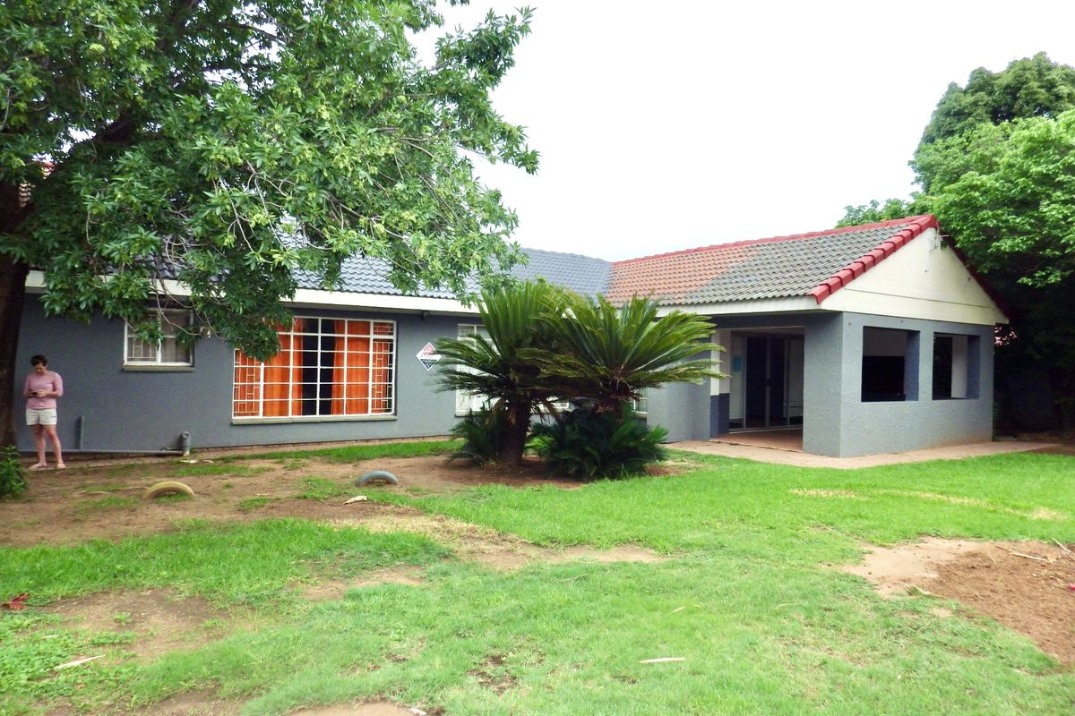 Rear view of the house featuring a covered patio area, tiled roof, and established garden space.