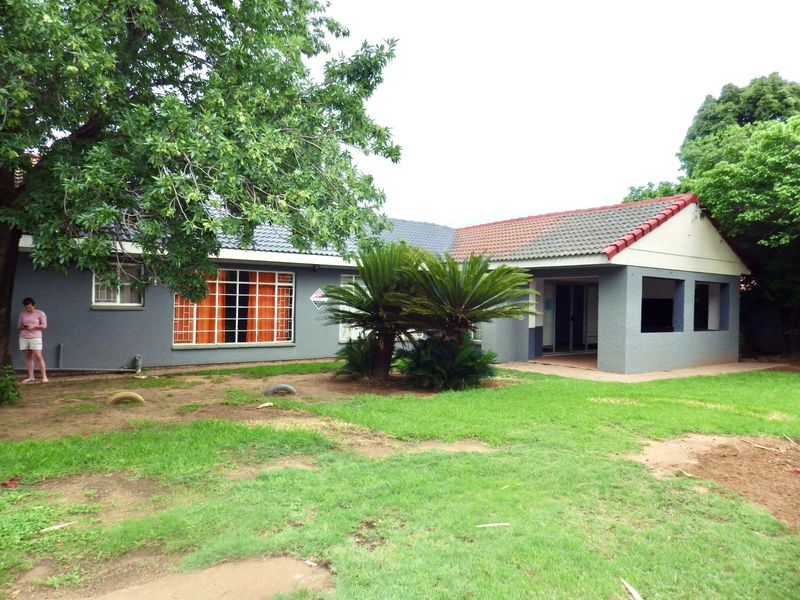 Rear view of the house featuring a covered patio area, tiled roof, and established garden space.