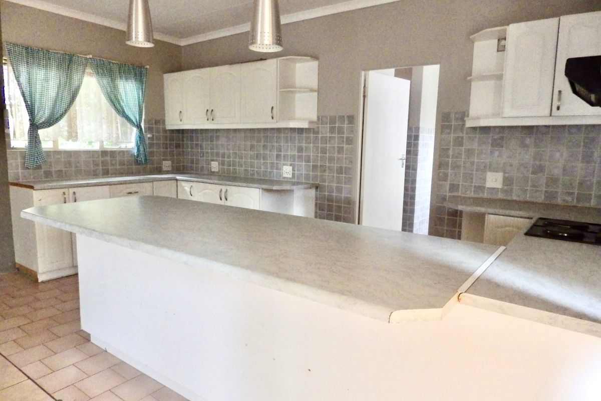 A functional kitchen featuring white cabinetry, laminate countertops, tiled backsplash, and a breakfast bar, offering a clean canvas for potential modern updates.